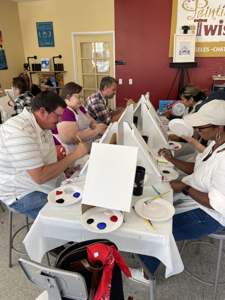 Participants in The Mystery Bus team building event paint canvases, engaging in a creative and collaborative experience.