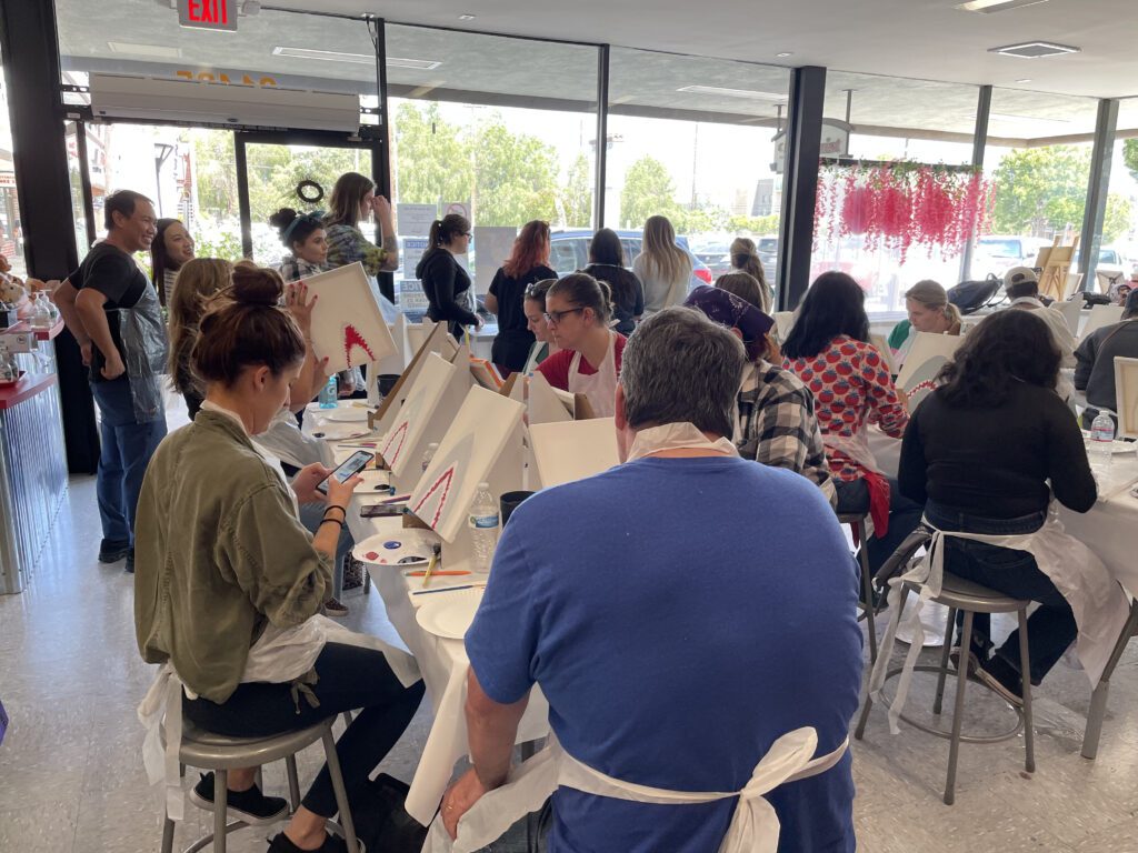 Team members participate in a painting activity during The Mystery Bus team building event, focusing on creativity and collaboration.