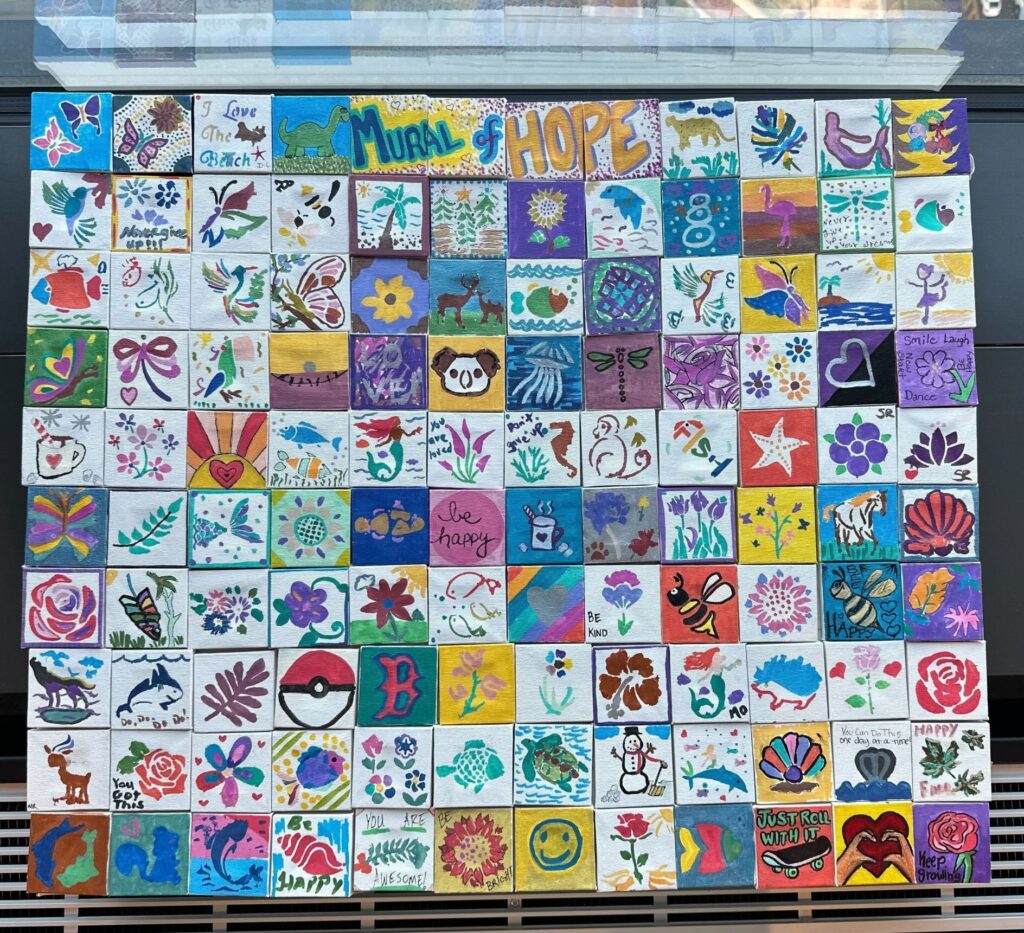 Completed colorful mini-mural titled 'Mural of Hope' made of individually painted tiles with various designs, created during the Make-A-Mini-Mural activity at a corporate charitable team building event called 'the Donation Station'.