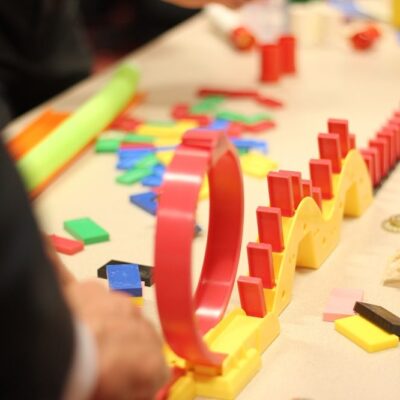 Colorful dominoes and game pieces set up in a chain reaction during the Domino Effect team building activity.