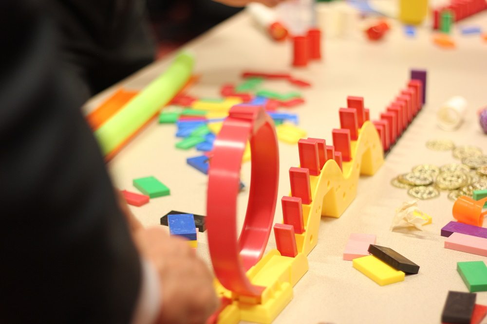 Colorful dominoes and game pieces set up in a chain reaction during the Domino Effect team building activity.