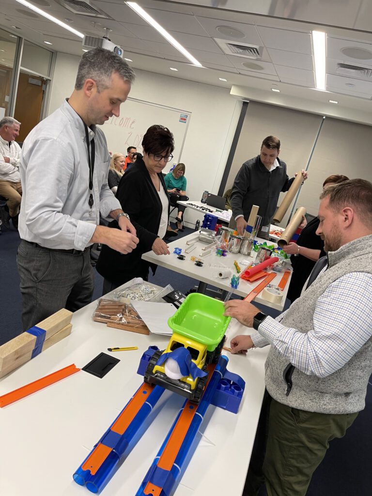 Participants engaged in the Domino Effect team building event, assembling creative contraptions using colorful materials.