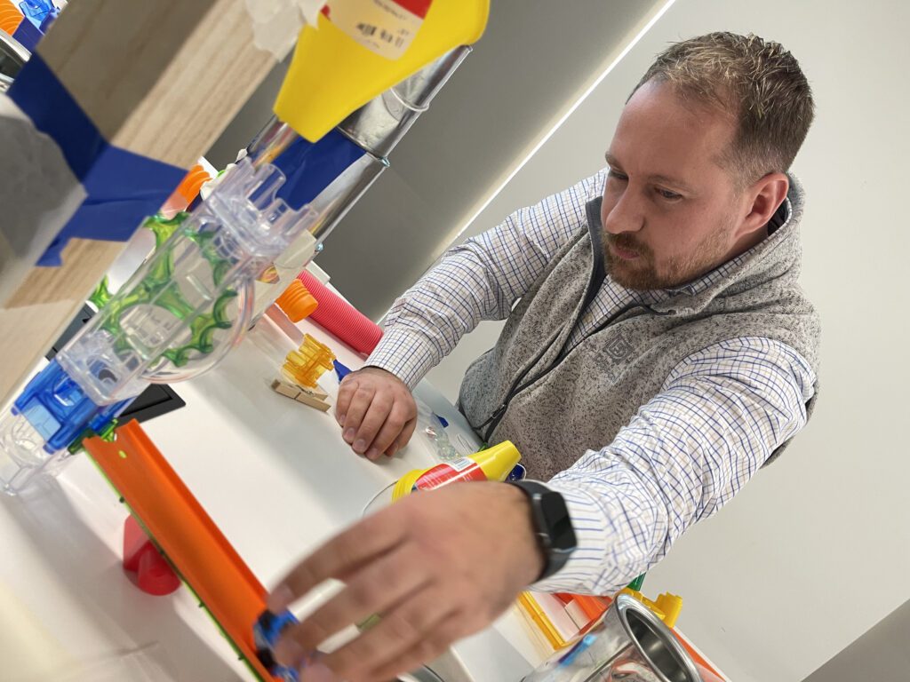 Participant working on a hands-on project during the Domino Effect team building event, focusing on creating Rube Goldberg-inspired contraptions to encourage creativity, problem-solving, and collaboration.