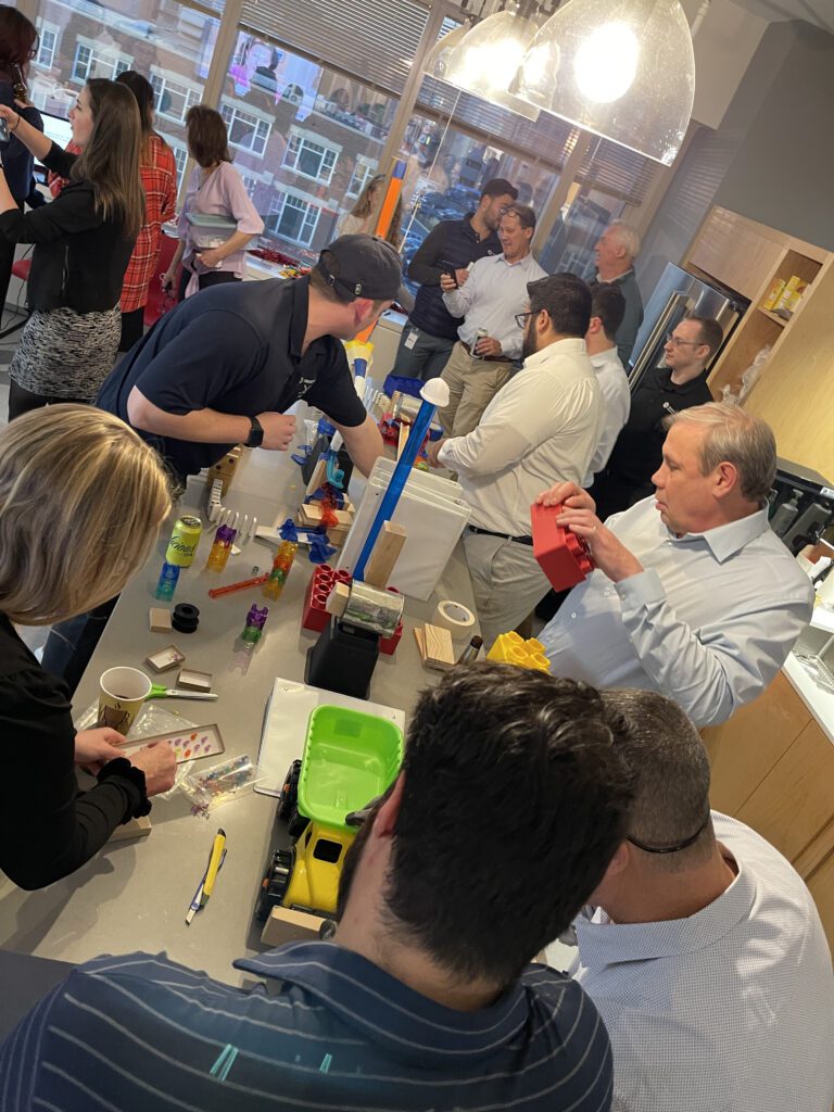 Group of participants collaborating and constructing complex devices during the Domino Effect team building event.