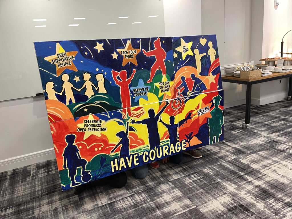 A vibrant mural created during The Big Picture team building event, featuring inspiring messages such as 