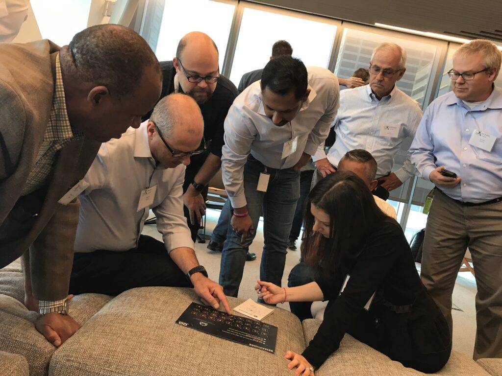 A team gathers closely around a puzzle board during The Infinite Loop team building event, collaborating to solve a challenge.