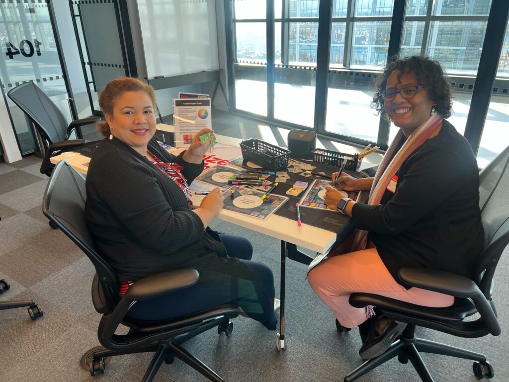 Two participants smiling while working on arts and crafts at a table during a corporate charitable team building event called 'the Donation Station'.