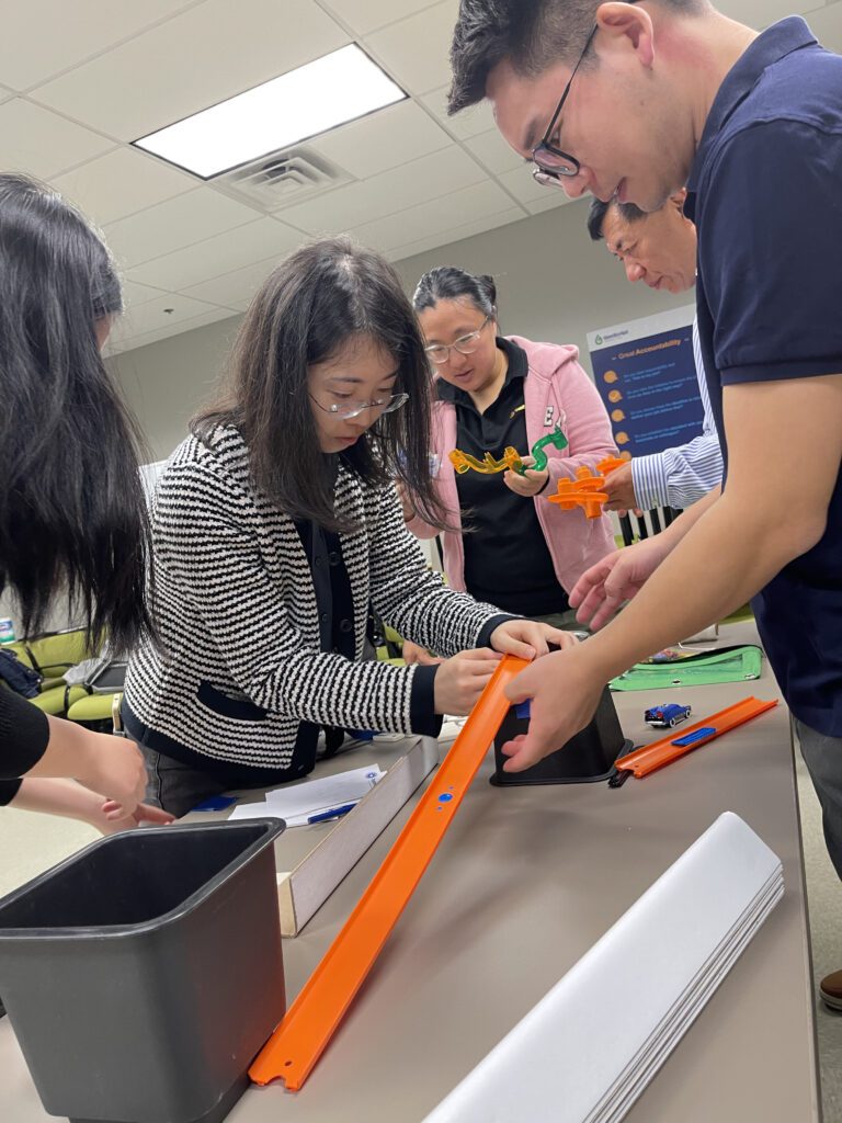 Team members assembling components of a track during the Domino Effect team building activity.