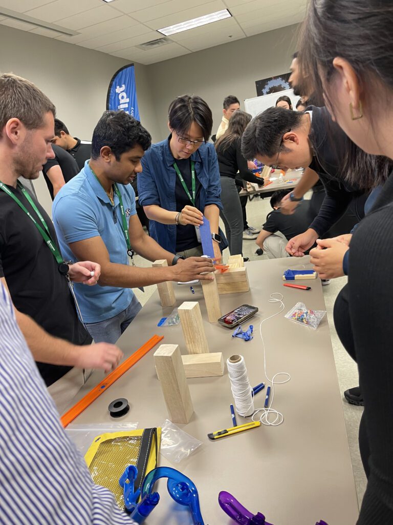 Team members working together on building a creative machine as part of the Domino Effect team building event.