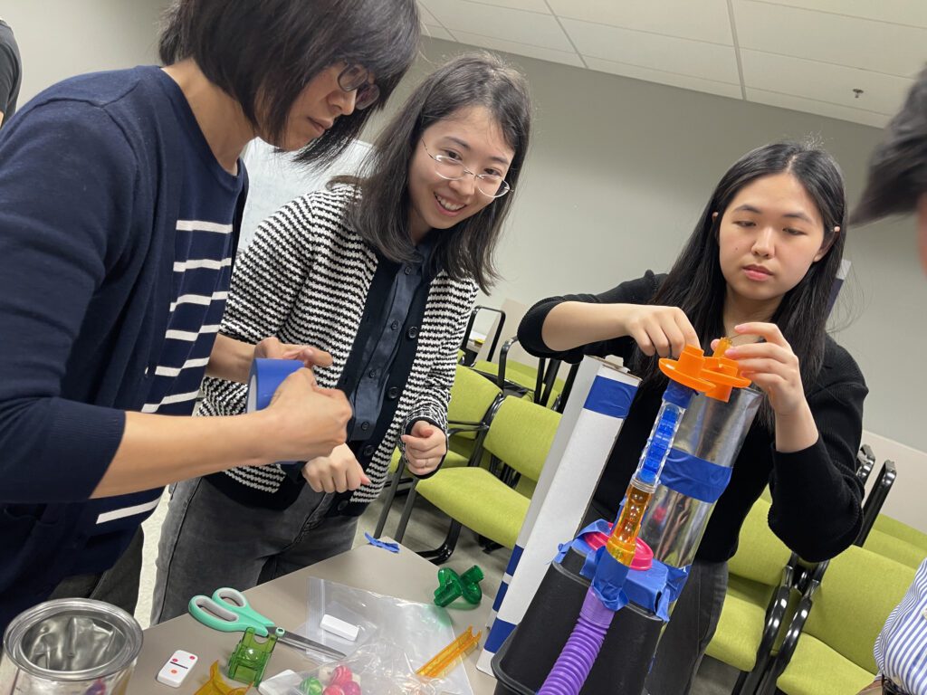 Team members focus on assembling a complex contraption during the Domino Effect team building event, working together to foster creativity and problem-solving.