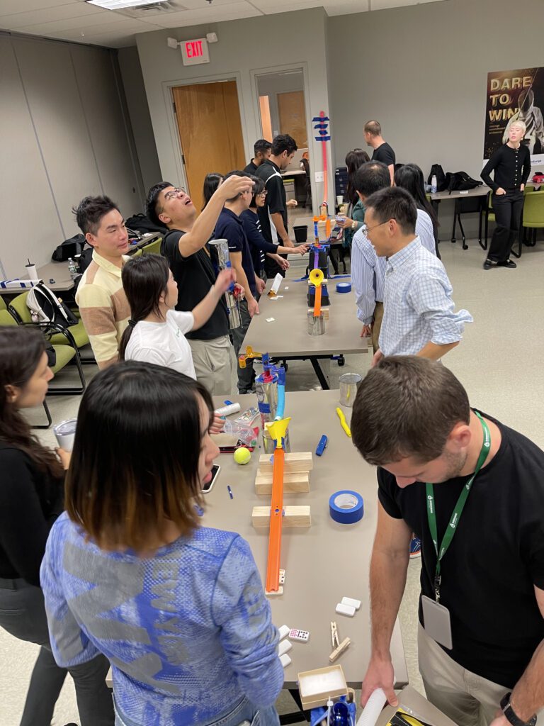 Participants working together to build a complex contraption during the Domino Effect team building activity.