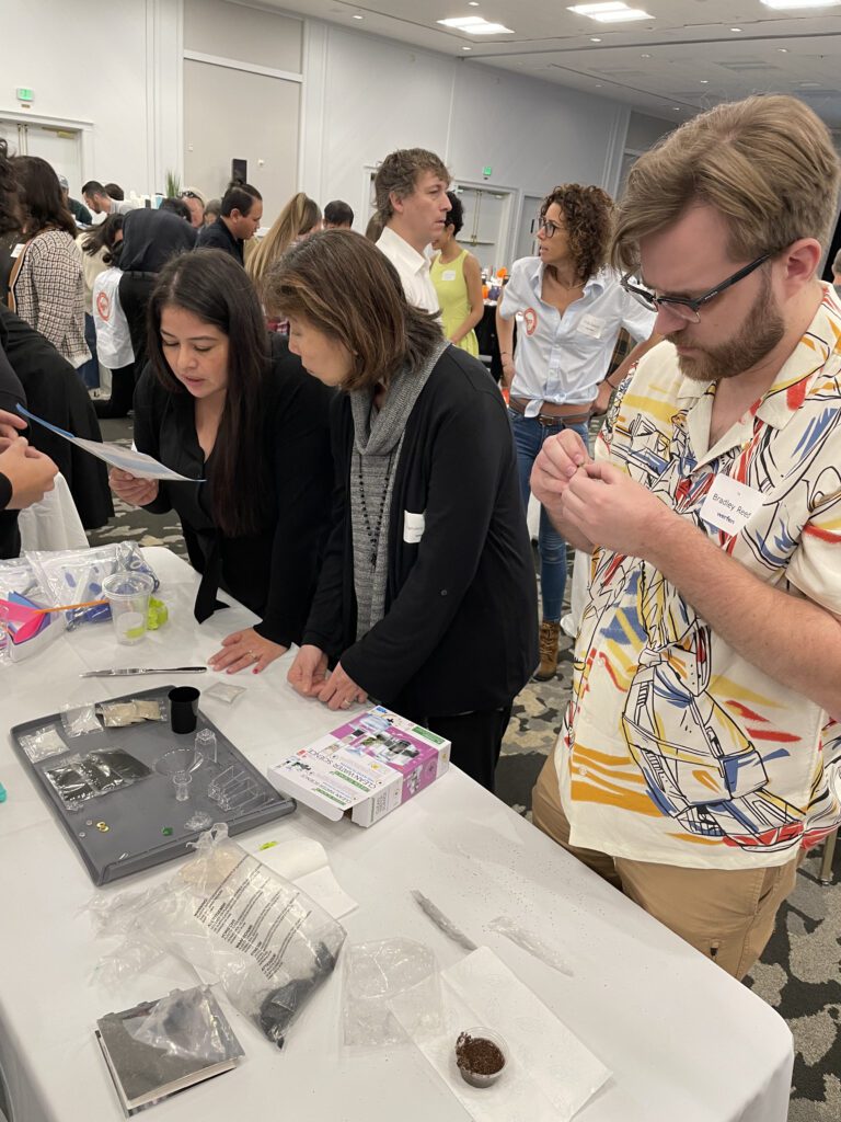 Participants at a Clean Water Connection team building event gather around a table, carefully reading instructions and assembling water filtration kits. The hands-on activity teaches them about water filtration technology and its importance in providing clean water to communities in need.