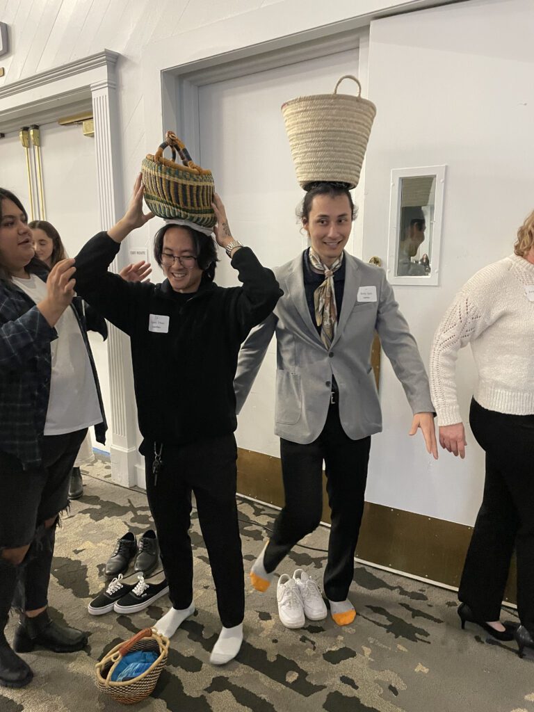 Two participants balance baskets on their heads as part of the water walk challenge during a Clean Water Connection team building event. The activity simulates the experience of carrying water long distances, which is a reality for many people in water-scarce regions.