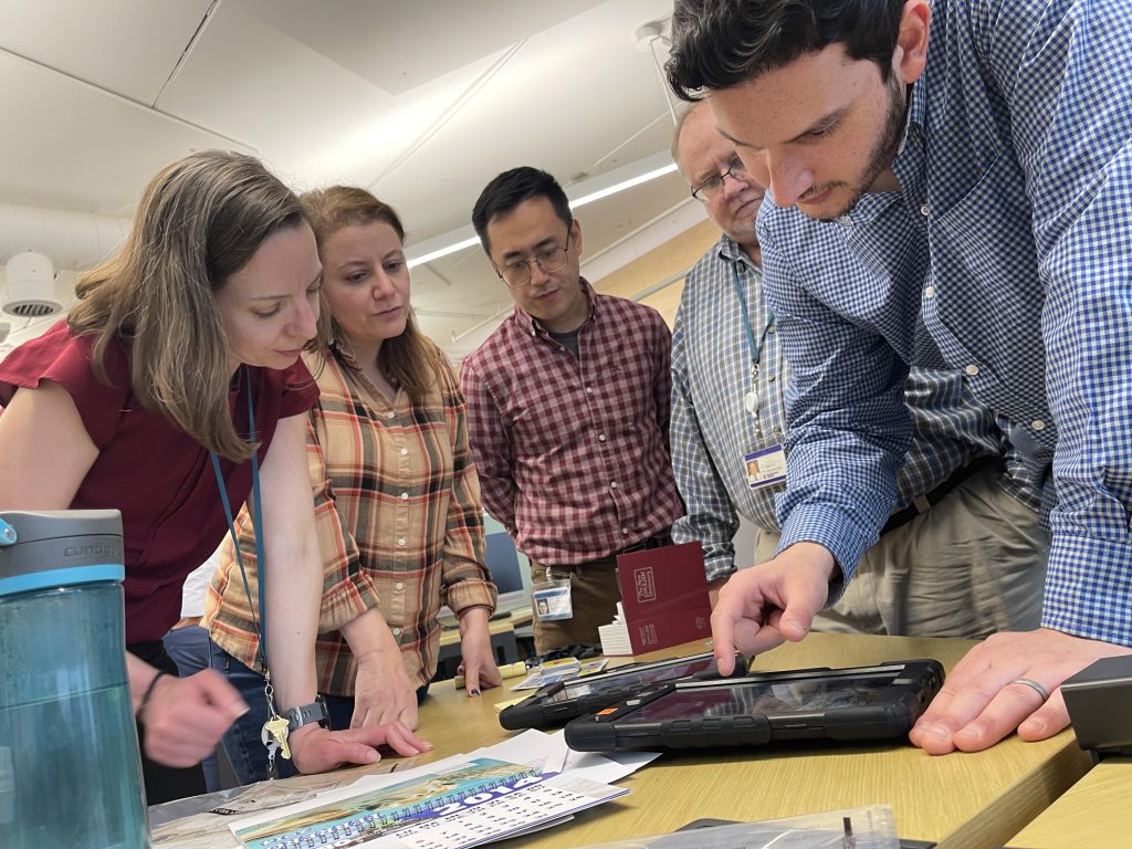 Team members collaboratively examining a virtual crime scene on a tablet during the Corporate CSI team building activity.