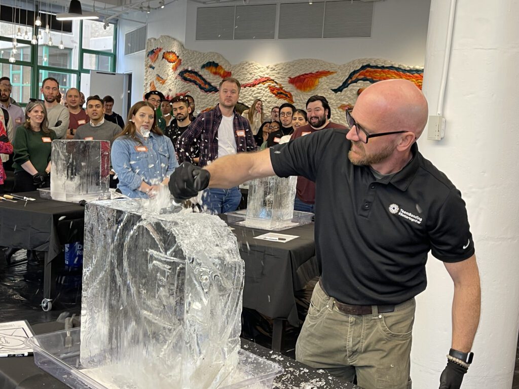 A facilitator demonstrating ice sculpting techniques while participants watch during a Team building Ice Sculpting workshop, encouraging collaboration and skill development.