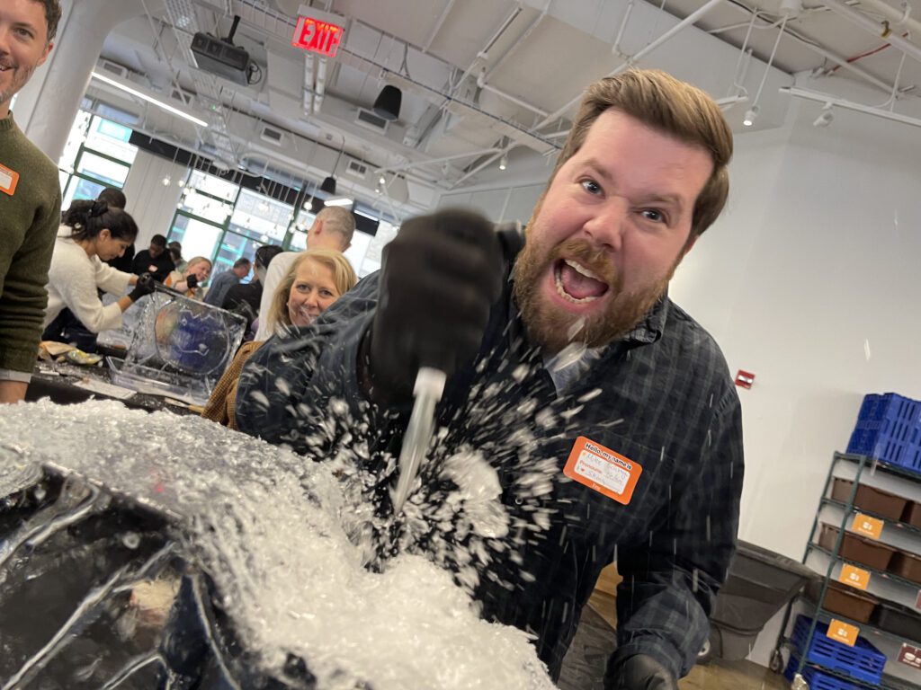 A participant energetically carves into an ice block during a Team building Ice Sculpting event, demonstrating focus and collaboration.