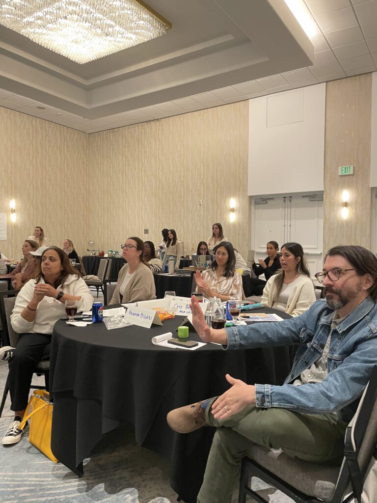 Participants attentively listen and engage during a board-breaking team building event, preparing to overcome personal and professional barriers.