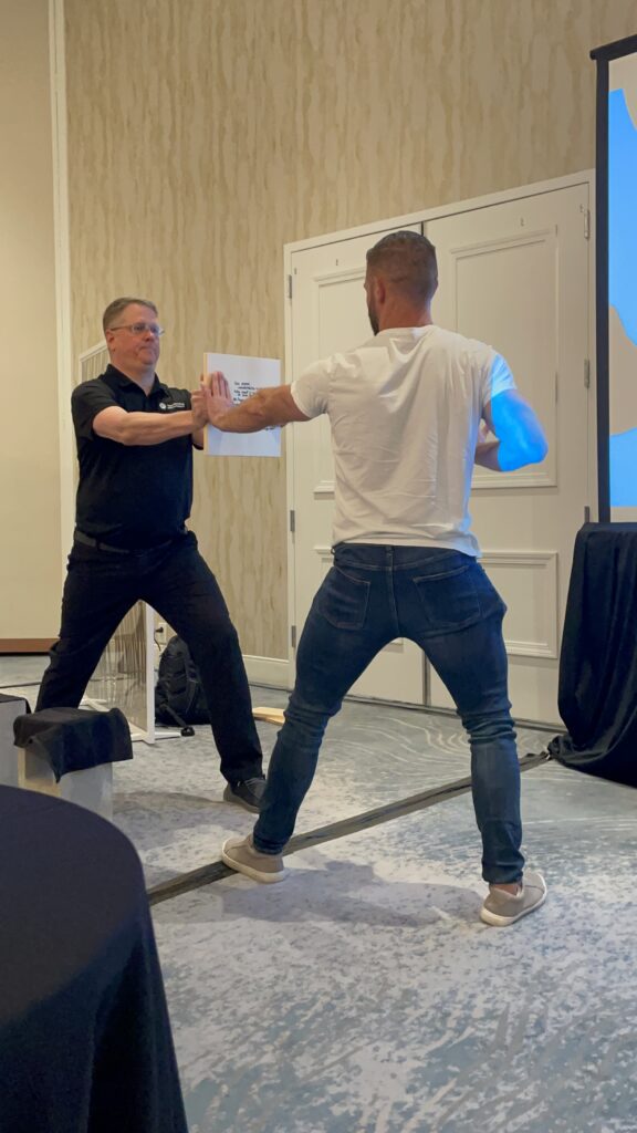 A participant prepares to break a board held by the facilitator during a team building activity designed to help overcome personal barriers.