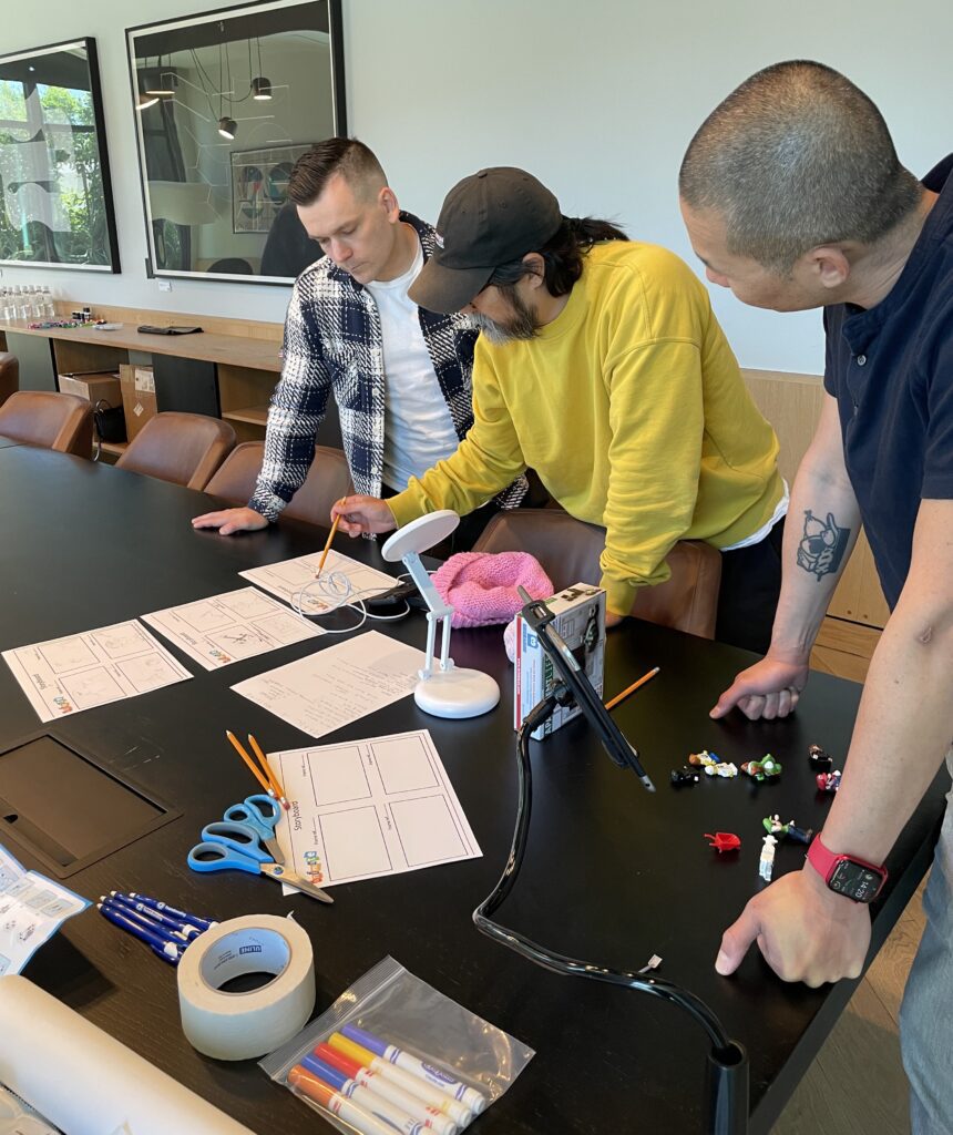 Team members collaborating on a storyboard for a stop motion animation project during a creative team building event.