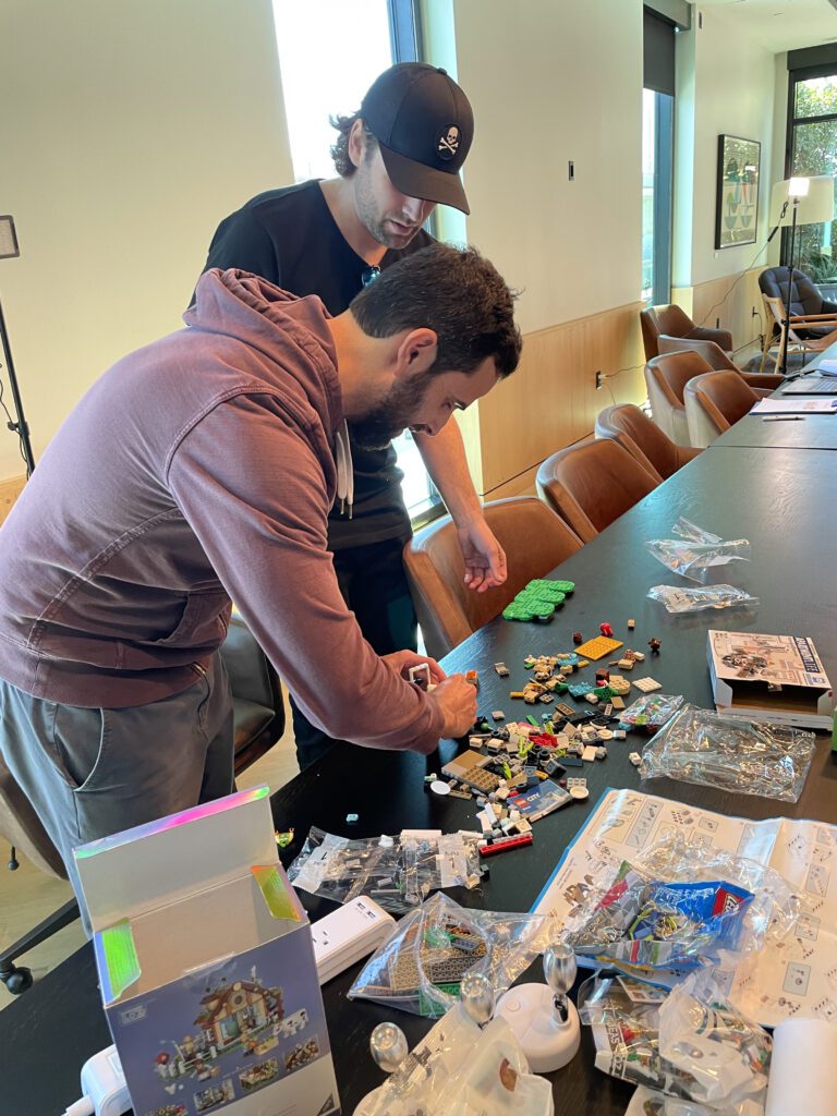 Two participants collaborating on a brick-building project during a stop motion animation team building activity, fostering creativity and teamwork.