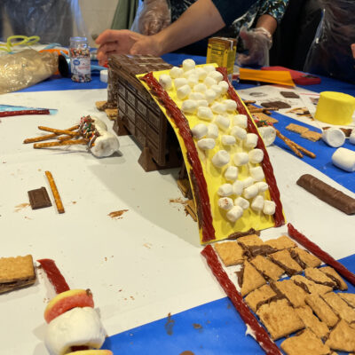 A chocolate bridge, covered with marshmallows and licorice, is creatively constructed during The Chocolate Challenge team building event, highlighting teamwork and edible engineering.