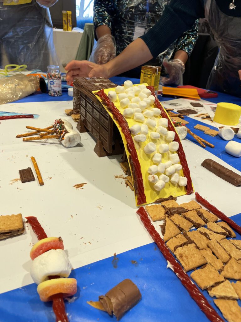 A chocolate bridge, covered with marshmallows and licorice, is creatively constructed during The Chocolate Challenge team building event, highlighting teamwork and edible engineering.