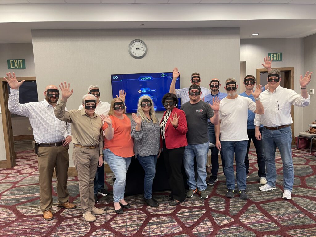 A group of participants pose for a group photo during The Infinite Loop team building event, wearing VR headsets after completing their collaborative virtual challenge.