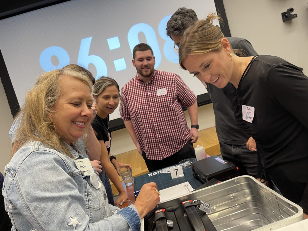 Team members collaborate and strategize with smiles during the Beat The Box team building event, unlocking new challenges as the clock counts down.