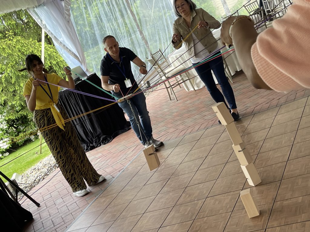 Team members collaborating in the Integrity team building event to complete a physical challenge by balancing wooden blocks using strings.