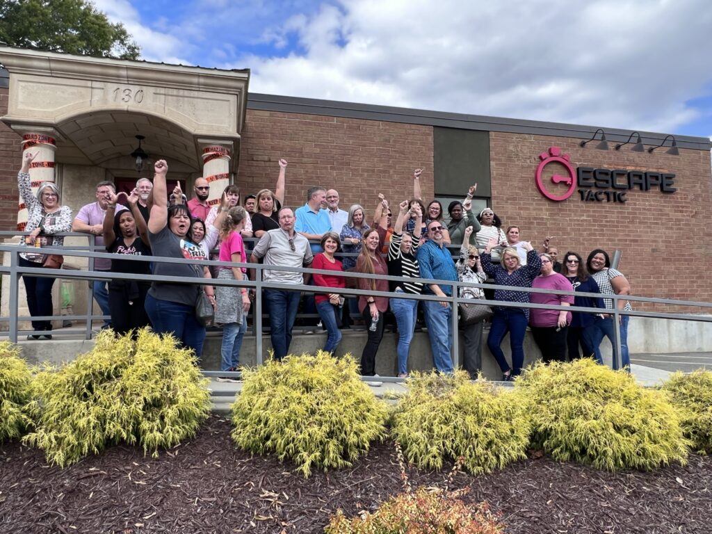 Team celebrating success after completing an escape room challenge during their Mystery Bus team building event, showcasing teamwork and problem-solving skills.