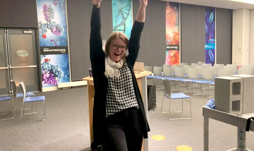 A participant celebrates with raised arms after successfully breaking a board during a team building activity focused on overcoming obstacles.