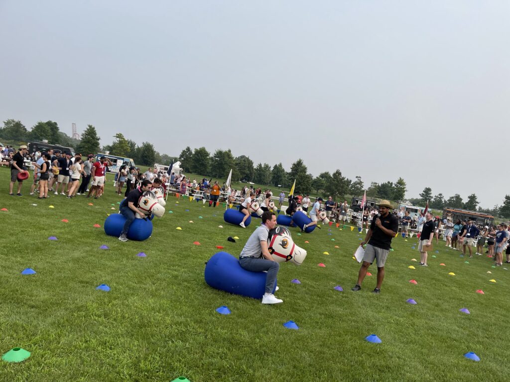 Participants competing in a relay race with inflatable horses during the Outrageous Games team building event.