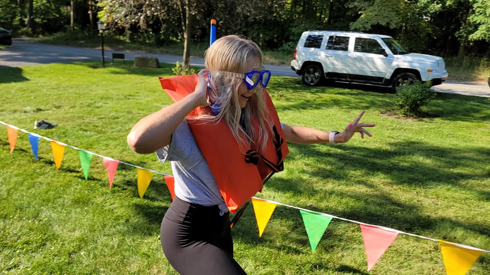 Participant in a life vest and goggles runs through a colorful relay course during an Outrageous Games team building event.