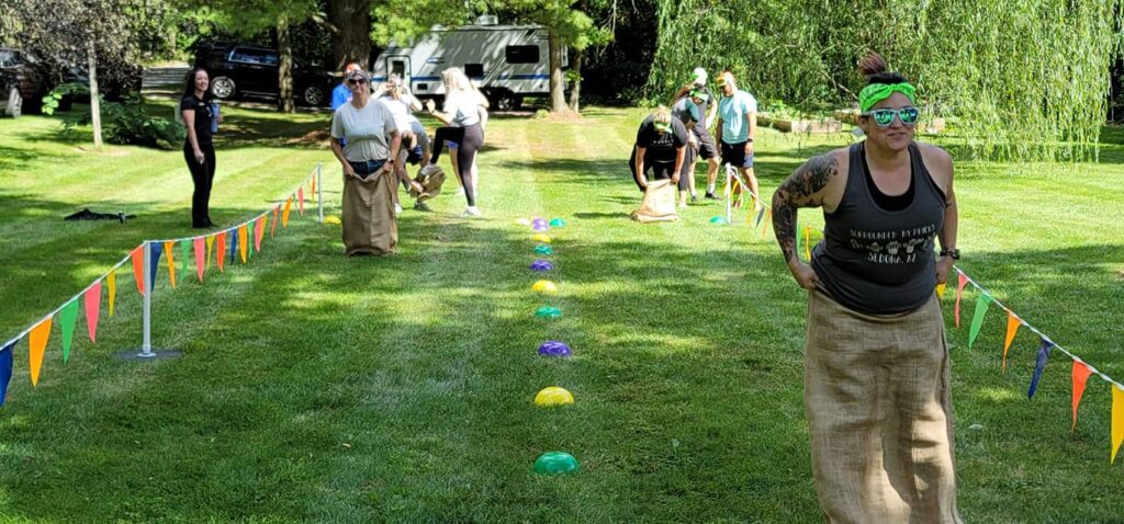 Participants racing in a classic sack race during the Outrageous Games team building event, enjoying friendly competition and teamwork.