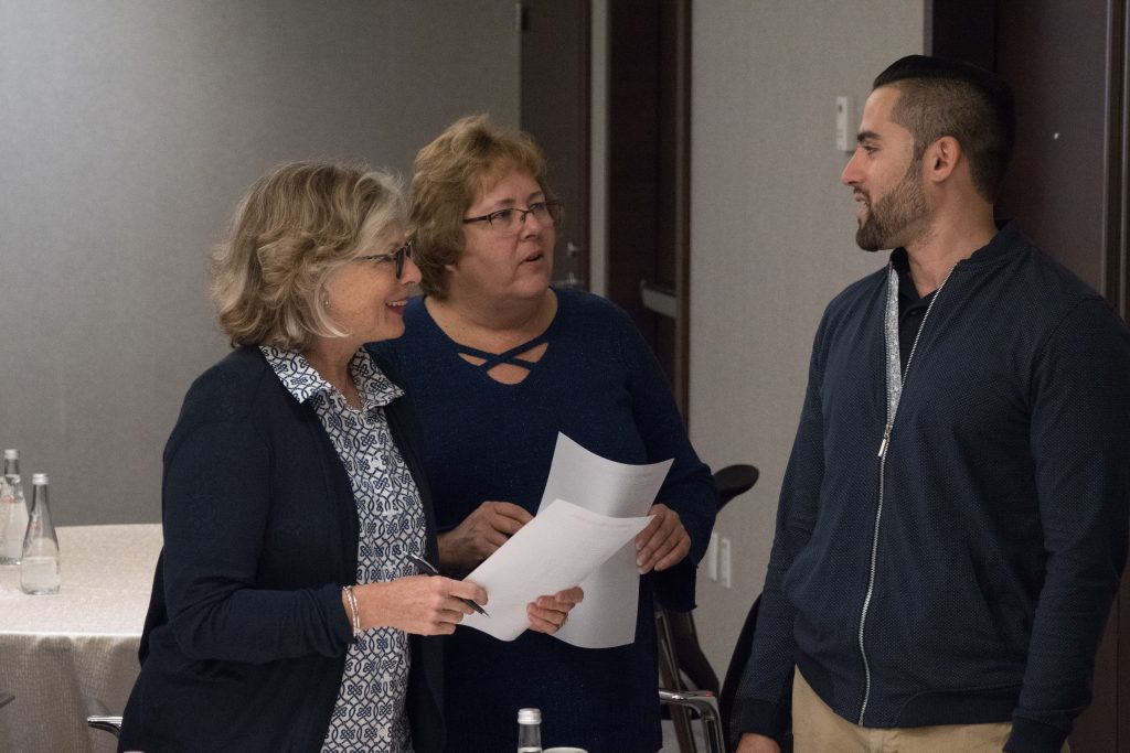 Three participants engaged in a conversation during the Team and Leadership DNA workshop, exchanging ideas and insights as they work through the activities.