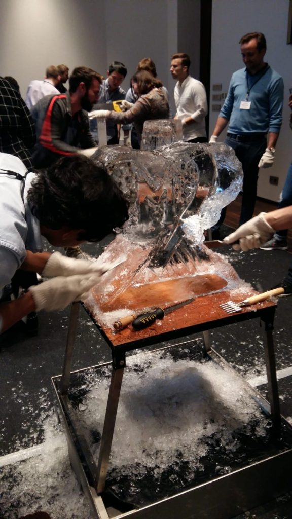 Participants work together to carve an intricate ice sculpture at a Team building Ice Sculpting event, demonstrating collaboration and creativity.