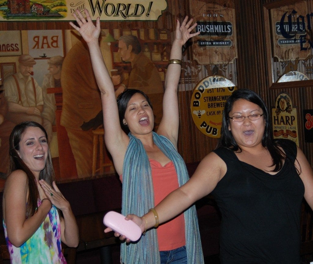 Three excited team members celebrate during a lively moment of the Pub Crawl Scavenger Hunt, capturing the thrill of teamwork and friendly competition.