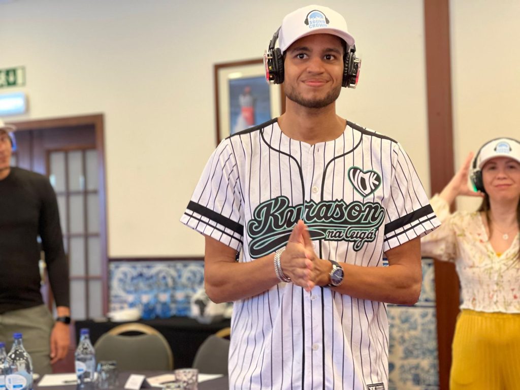 Participants actively engaging in the Sound Crowd event, wearing silent headphones, with one person in a baseball jersey smiling and clapping, while another gestures in the background.