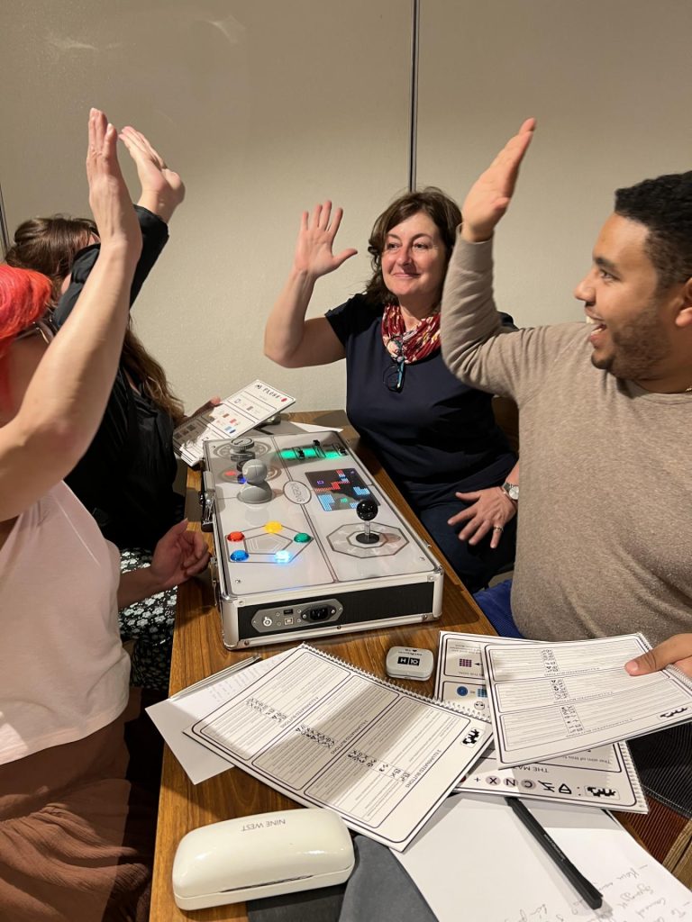 Excited participants high-five during the Team Synergy retro gaming team building activity, celebrating their success and teamwork around a game console.