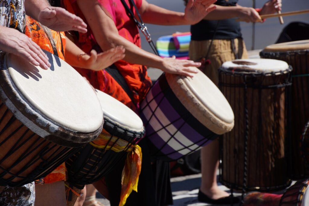 Participants in the Drumming Up A Team event play percussion instruments, collaborating to create a unified rhythm and building team spirit through music and engagement.