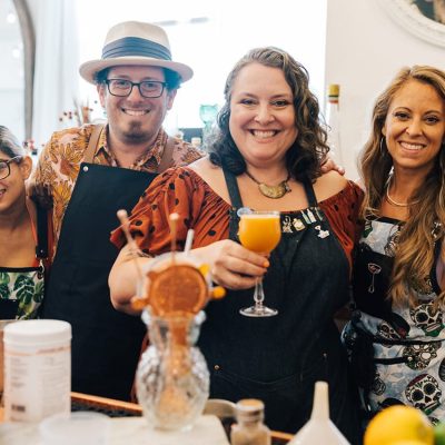 Team members proudly posing with their cocktail creations during a mixology class. The fun, interactive event encourages creativity and teamwork while learning the art of cocktail crafting.