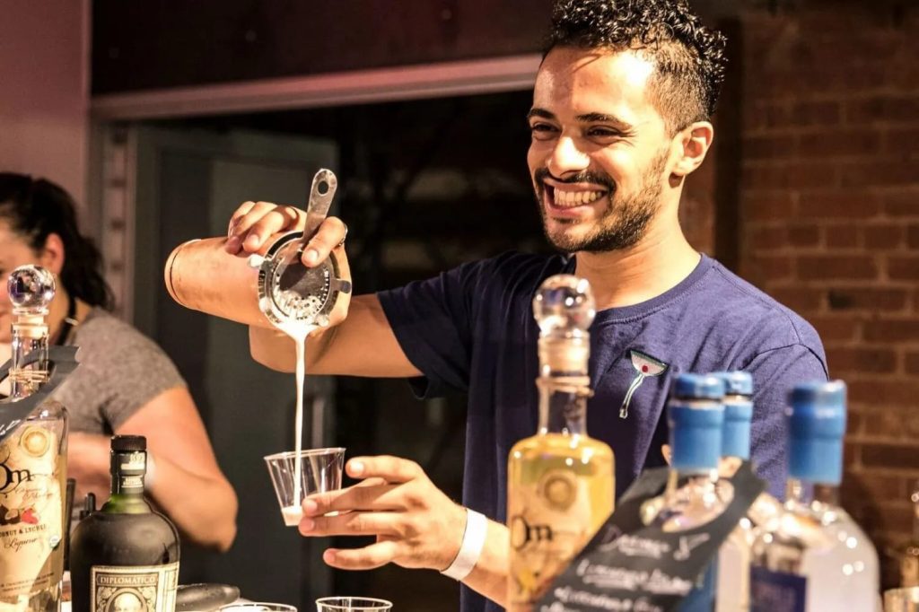 Team member pouring a cocktail during a mixology class. The event fosters teamwork and creativity as participants learn the art of cocktail crafting while enjoying a fun, interactive experience.