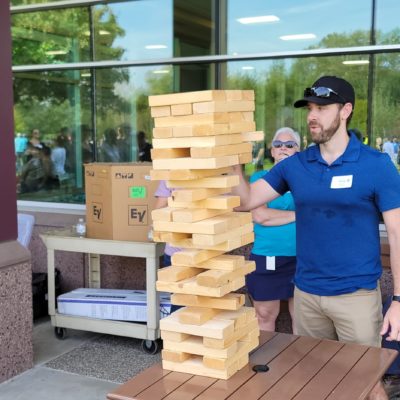 The image shows participants engaging in a giant outdoor Jenga game, a popular activity in the 