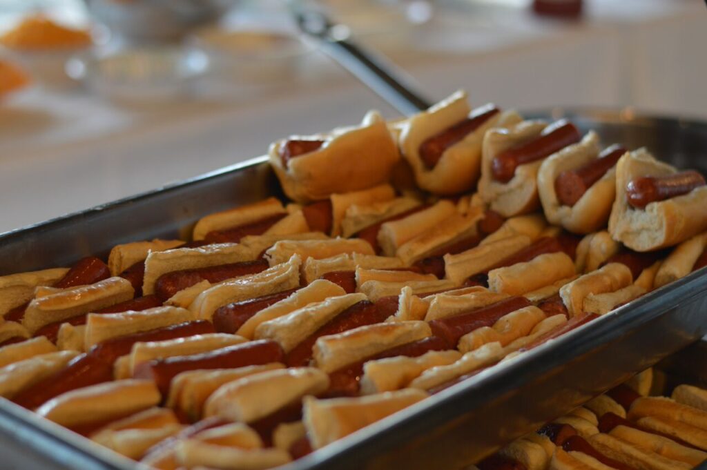 A large tray filled with mini hot dogs, each neatly placed in a small bun. The hot dogs are arranged in rows, making them easy to serve at a food truck challenge team building event.