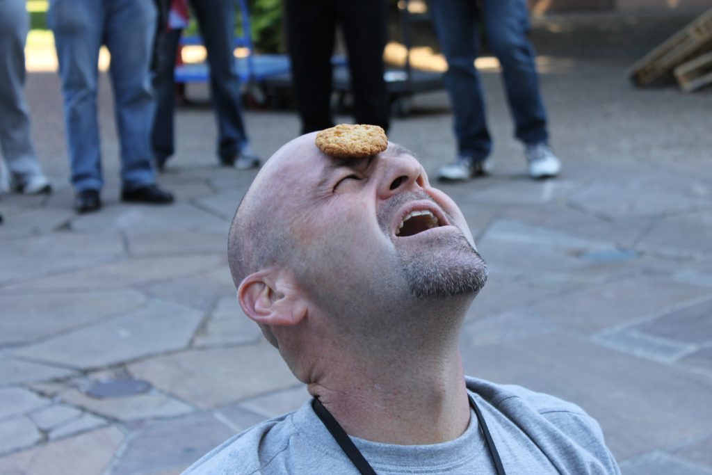 Participant attempting the 'Cookie Face' challenge in the In It To Win It team building event. The fast-paced competition promotes laughter, teamwork, and friendly rivalry as teams compete in fun 60-second games.